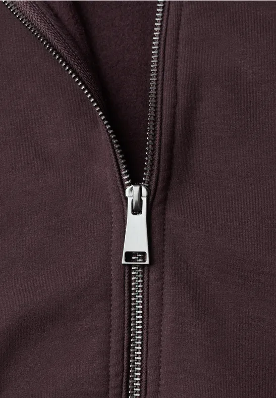 Nahaufnahme eines Metallreißverschlusses an einer dunkelvioletten Jacke.