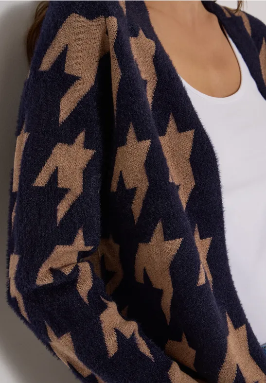 Une personne porte une veste bleu marine en peluche avec des étoiles beiges sur un haut blanc.