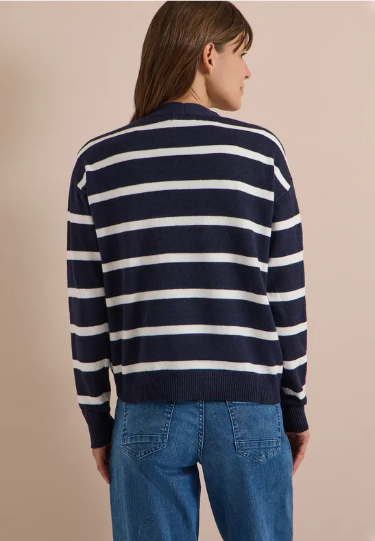 Frau von hinten in navy-weiß gestreiftem Pullover und blauen Jeans vor neutralem Hintergrund.