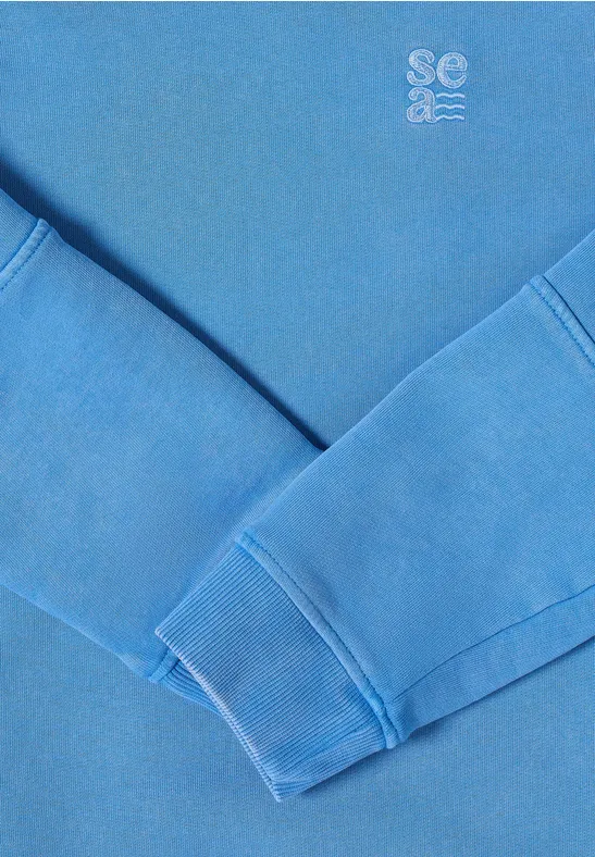 Pull bleu aux manches croisées, petit logo en haut à droite
