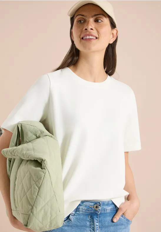 Vrouw in wit T-shirt met een groen doorgestikt tas.