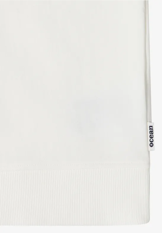 Close-up van een wit kledingstuk met geribde zoom en zijlabel 'Ocean'.