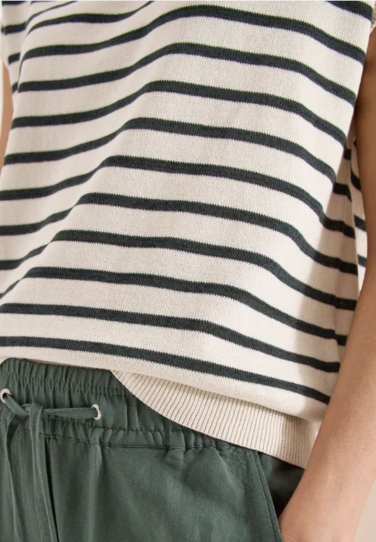 Nahaufnahme einer Person mit gestreiftem Oberteil und grüner Bundhose mit Kordelzug.