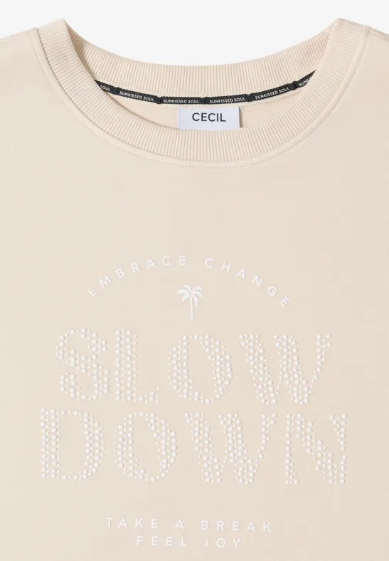 Beiges CECIL T-Shirt mit aufgenähten Strasssteinen, Schriftzug "SLOW DOWN" und Palmenmotiv.