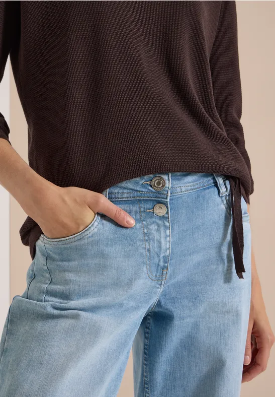 Helle Jeans mit doppelter Knopfleiste und braunem Pulloverteil.