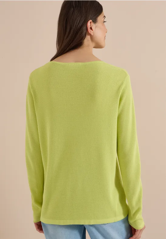 Model von hinten in hellgrünem Langarmshirt mit weiter Passform.