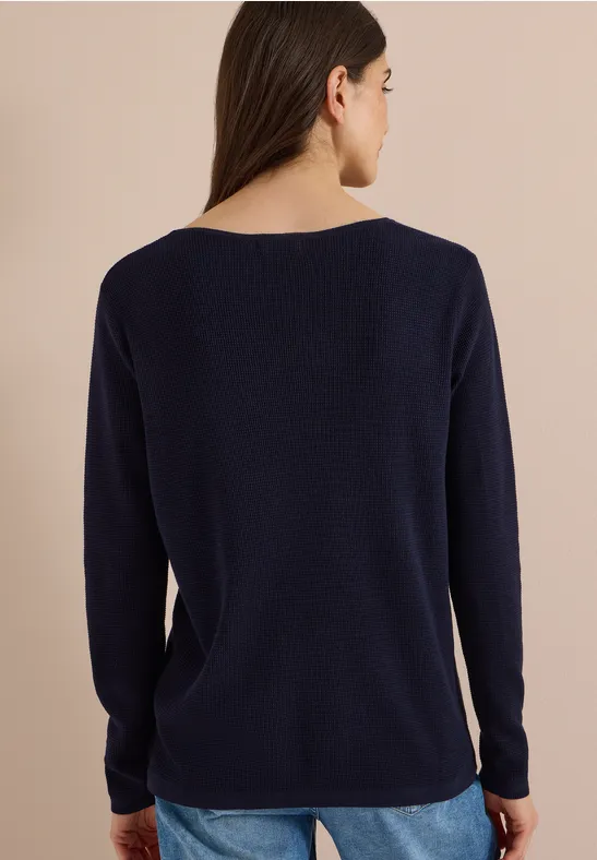 Rückenansicht einer Frau in marineblauem, langärmligem Pullover mit weiter, schlichter Form.