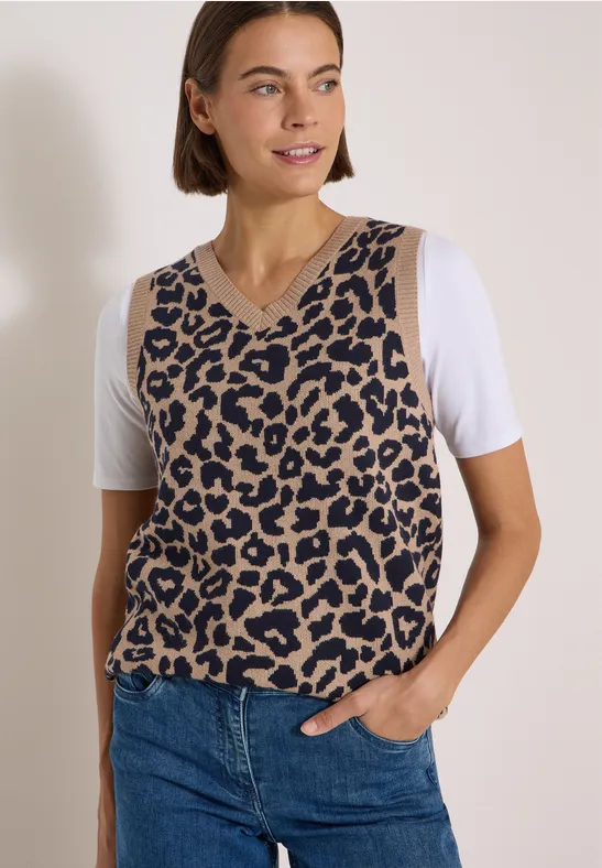 Frau in Jeans und ärmellosem Pullunder im Leopardenmuster über weißem T-Shirt.