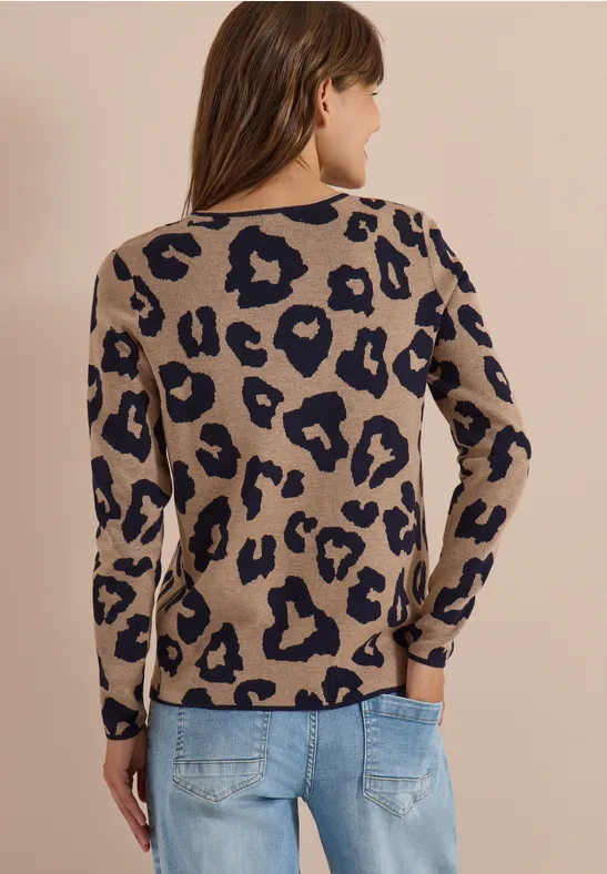 Vrouw van achteren in een beige trui met luipaardprint en blauwe spijkerbroek