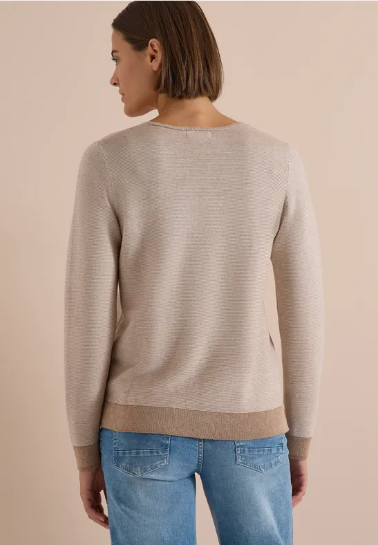 Vue de dos d'une femme en pull beige clair et jean bleu.