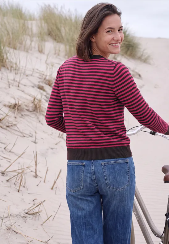 Lachende vrouw op het strand naast haar fiets kijkt achterom.