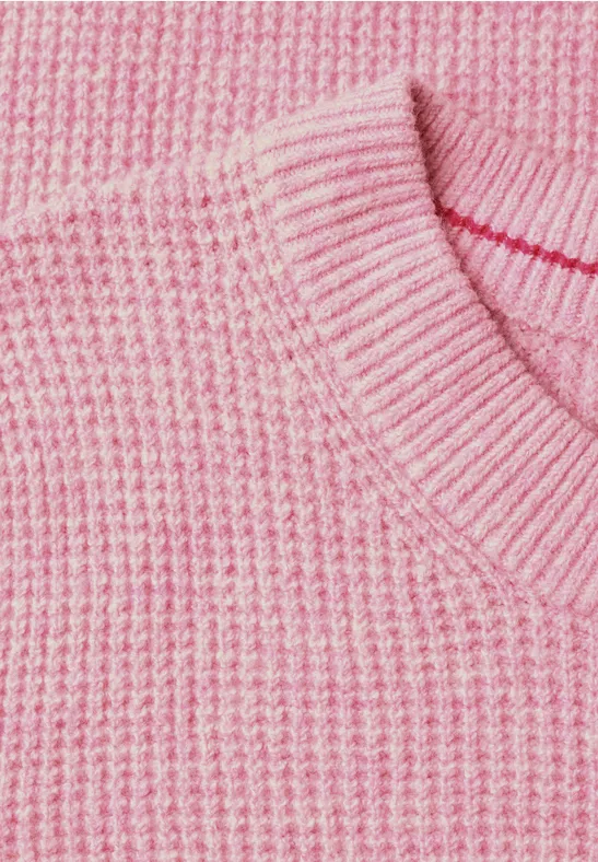 Close-up van een roze gebreide trui met ronde hals.