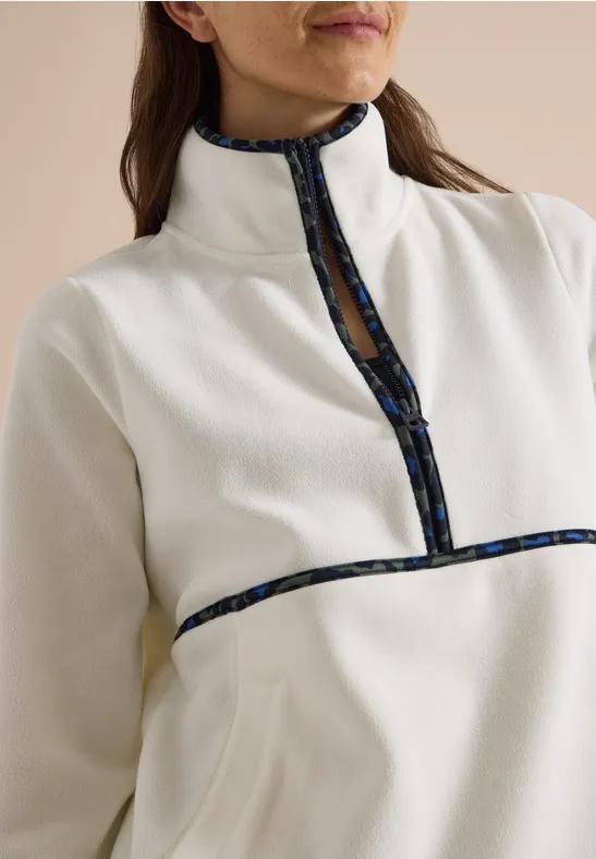Vrouw met witte fleece trui met halve ritssluiting en contrasterende donkerblauwe print