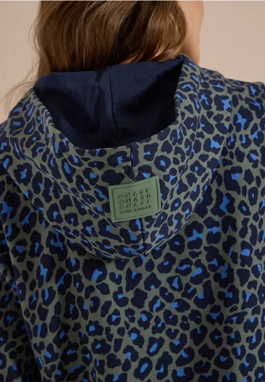 Graue Kapuzenjacke mit blauem Leopardenmuster und dunkelblauem Innenfutter, grünem Label am Rücken.