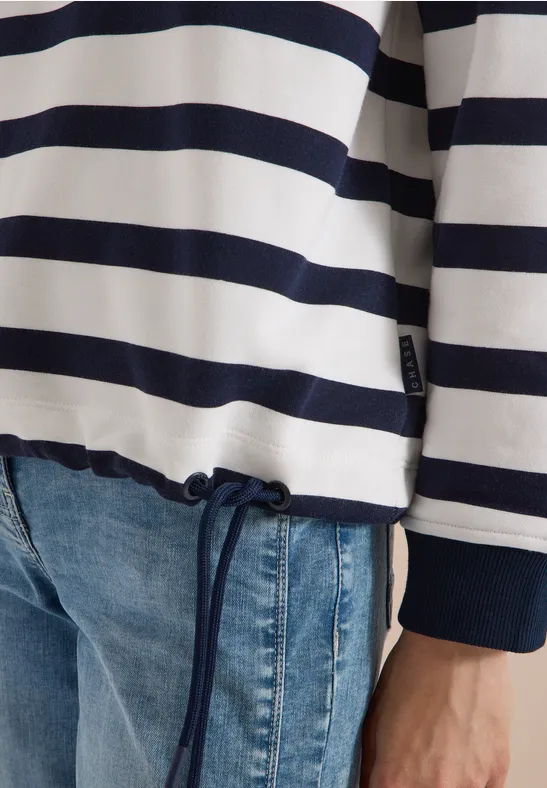 Personne porte un pull à rayures bleu et blanc avec cordon de serrage et un jean.