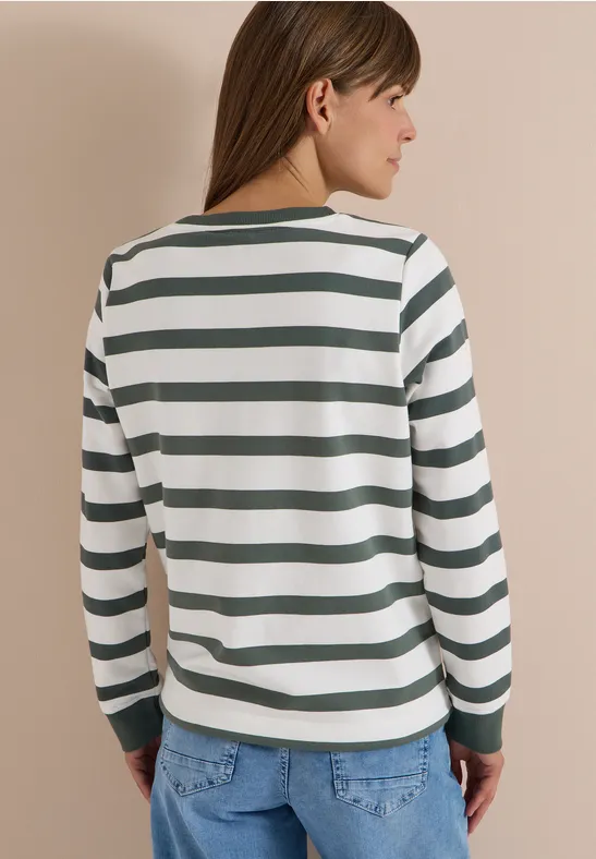 Vue de dos d'une personne portant un t-shirt à manches longues blanc et vert rayé avec un jean.