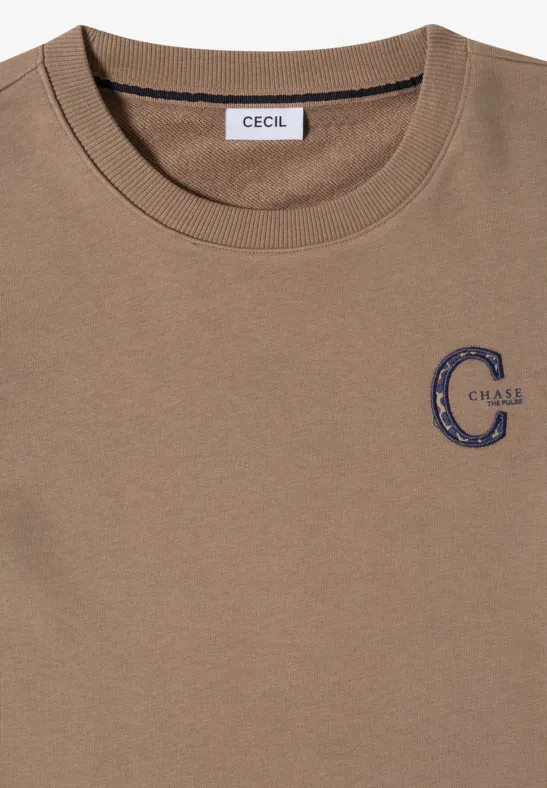 Beiges T-Shirt mit Rundhalsausschnitt, Label „CECIL“ im Nacken und blauem „C-ABLE“-Print auf der Brust.