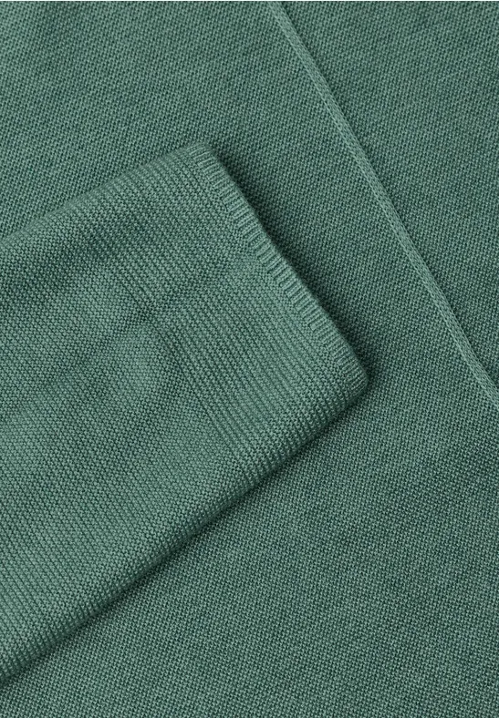 Ein grüner Strickpullover mit gerippten Bündchen.