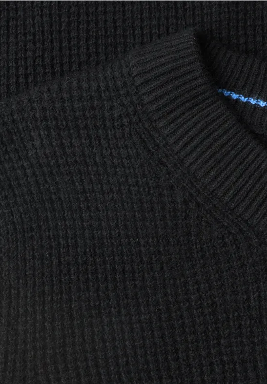 Gros plan d'un pull en maille noire côtelée avec encolure ronde.