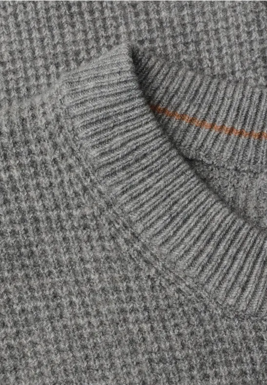 Nahaufnahme eines grauen Strickpullovers mit Waffelmuster und geripptem Kragen.