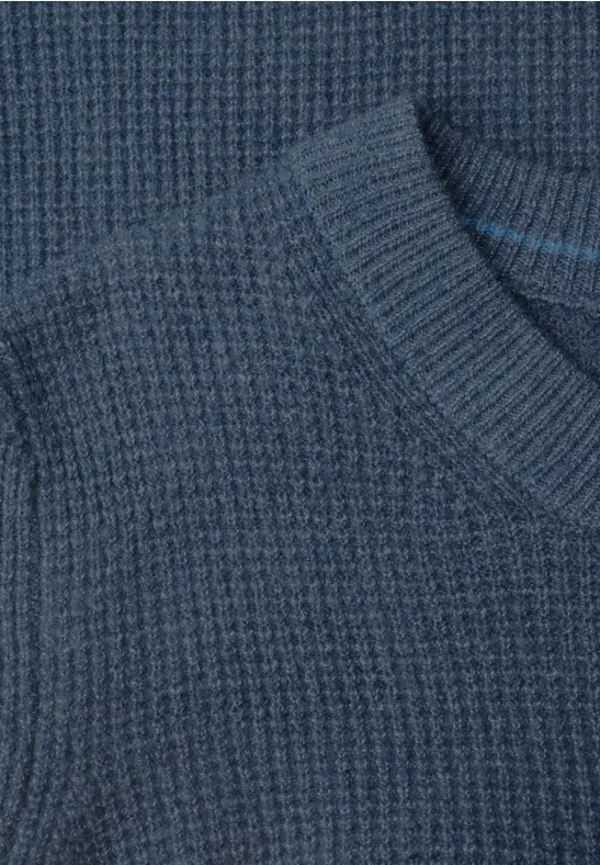 Nahaufnahme eines dunkelblauen Strickpullovers mit Waffelstruktur.
