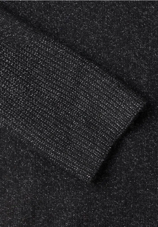 Nahaufnahme eines schwarzen, glitzernden Strickstoff-Ärmels mit Bündchen.