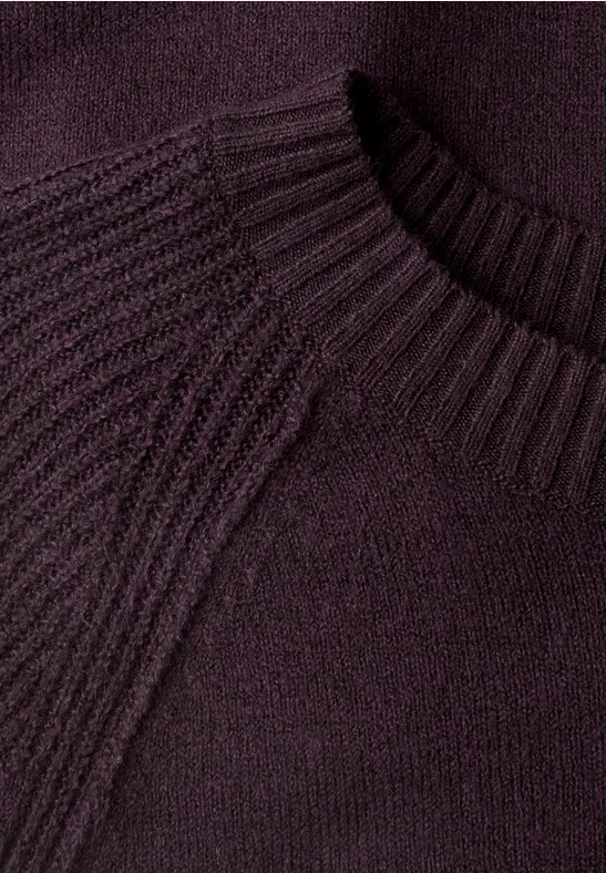 Nahaufnahme eines lila Strickpullovers mit geripptem Rundhalsausschnitt