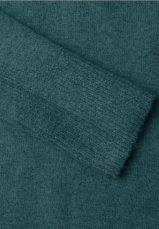 Grob gestrickter, gefalteter Stoff in dunklem Türkis