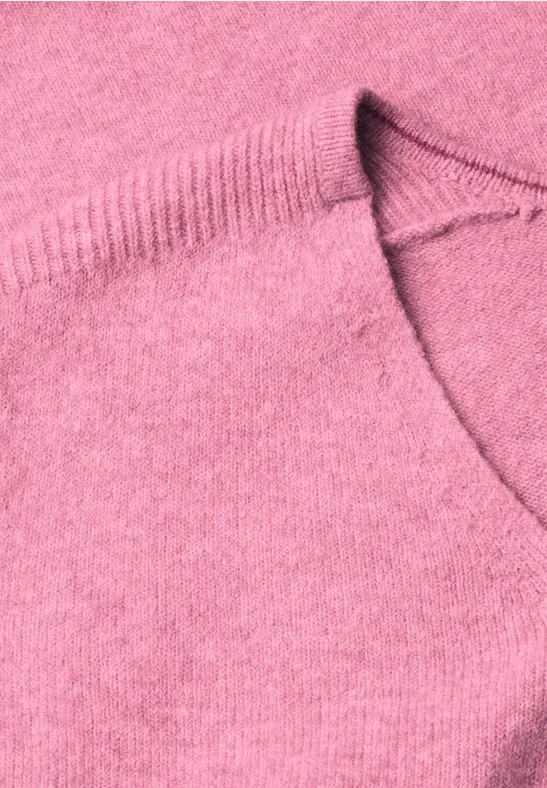 Close-up van een roze gebreide trui met ronde hals en fijne structuur.