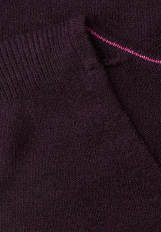 Nahaufnahme eines dunkelvioletten Strickstoffs mit Tasche und rosafarbenem Zierstich.
