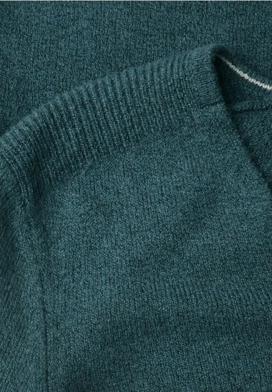 Nahaufnahme eines tealfarbenen Strickpullovers aus weichem, strukturiertem Garn.