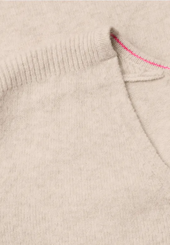 Nahaufnahme einer hellbeigen Wolltasche mit feiner Struktur und pinkem Stich am Saum.