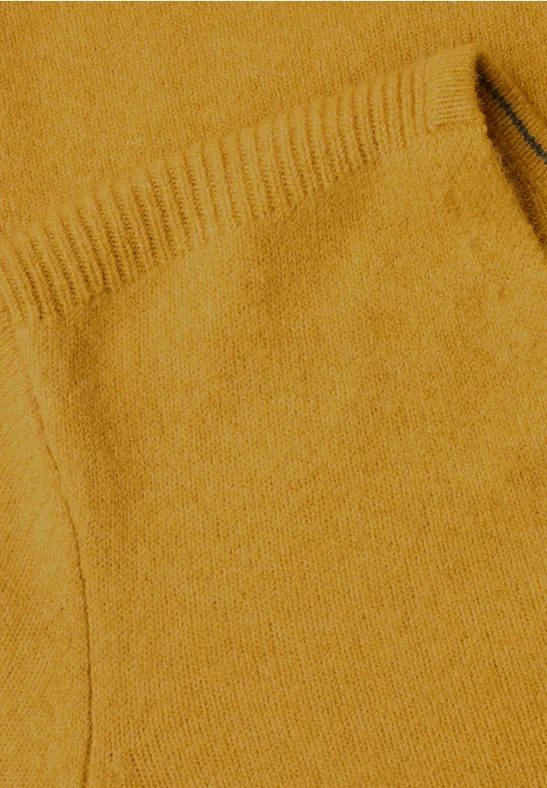 Nahaufnahme eines senffarbenen Strickpullovers mit Tasche und feiner Struktur.