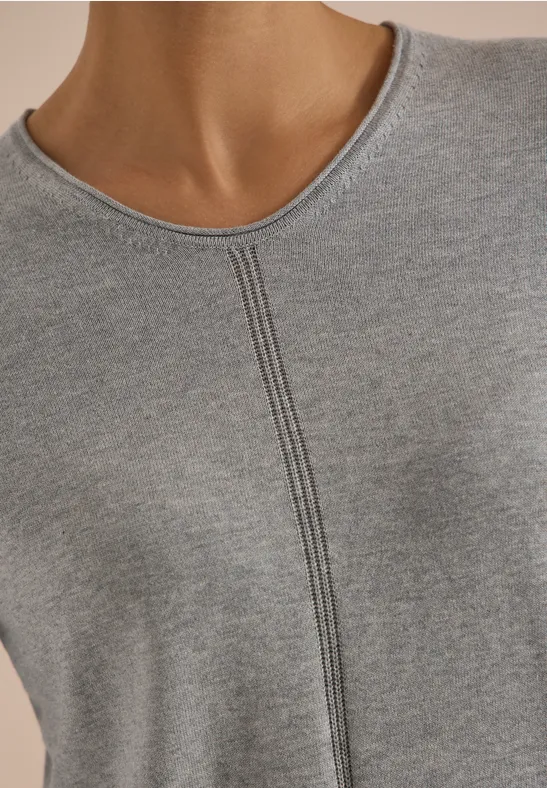 Nahaufnahme des Oberkörpers einer Person in grauem, fein geripptem Shirt mit zentraler Naht.