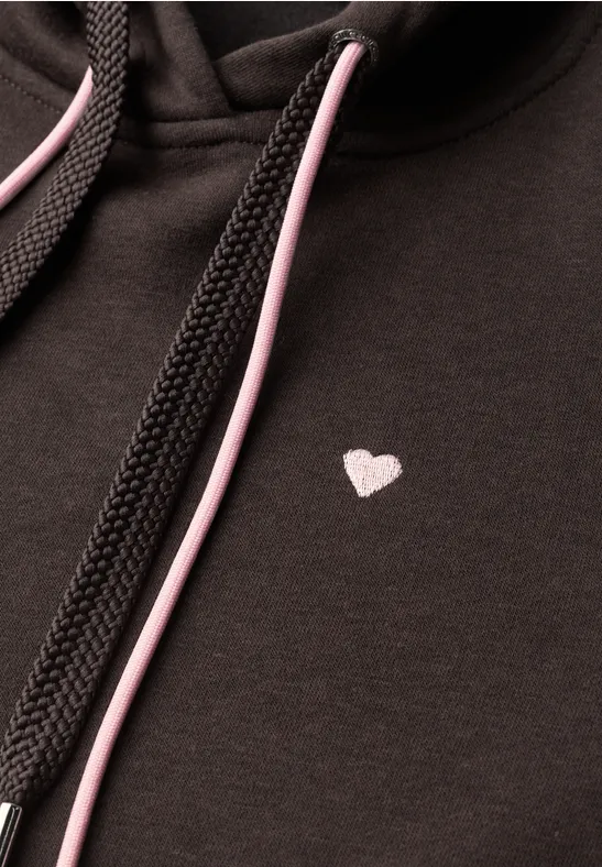 Schwarzer Hoodie mit kleinem weißem Herzmotiv auf der Brust und rosa-schwarzen Kordeln.