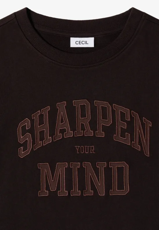 Schwarzes T-Shirt mit Rundhalsausschnitt, brauner Aufdruck 'SHARPEN YOUR MIND' und Markenlabel 'CECIL' innen am Kragen.
