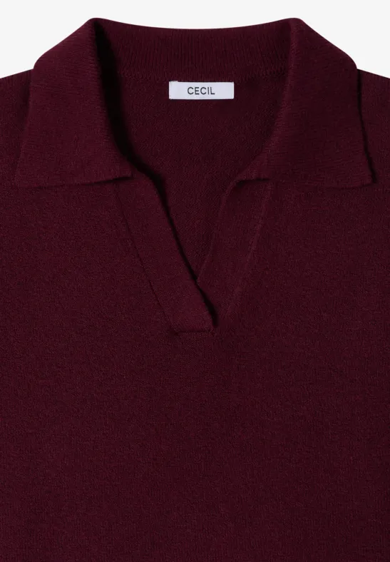 Un polo en maille bordeaux avec col et encolure en V sans boutons.