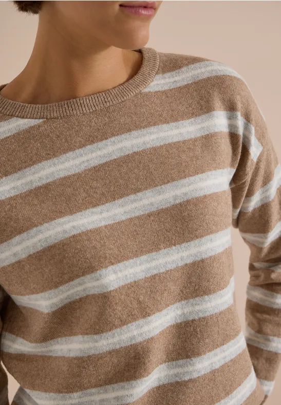 Pull beige à rayures blanches horizontales, porté par une femme, partie supérieure visible.