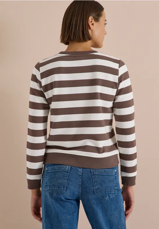 Frau von hinten in gestreiftem Braun-Weiß-Pullover und blauen Jeans, kurzhaarig.
