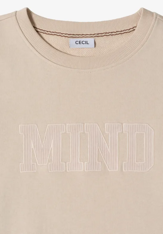 T-shirt beige avec inscription 'MIND' en contours blancs et étiquette 'CECIL' à l'intérieur
