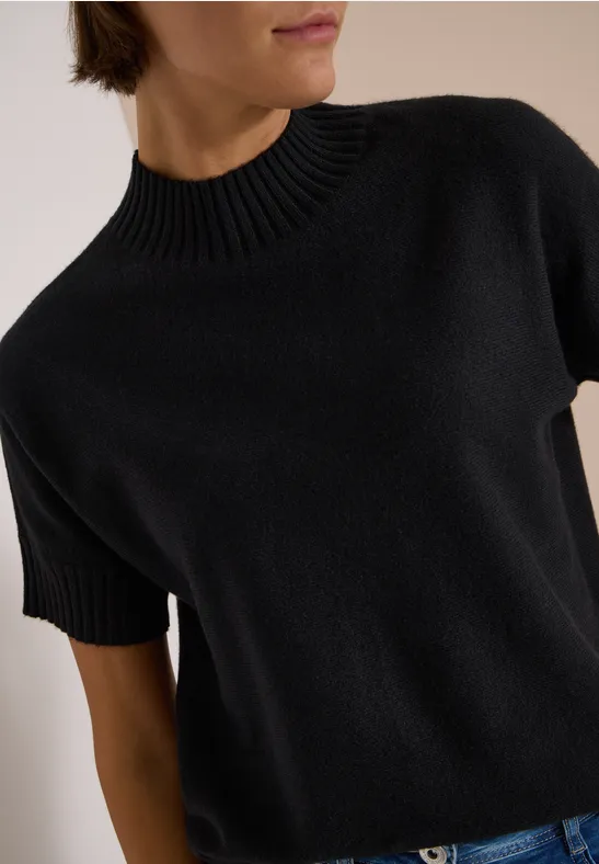 Pull femme noir en maille avec manches courtes et col montant côtelé.