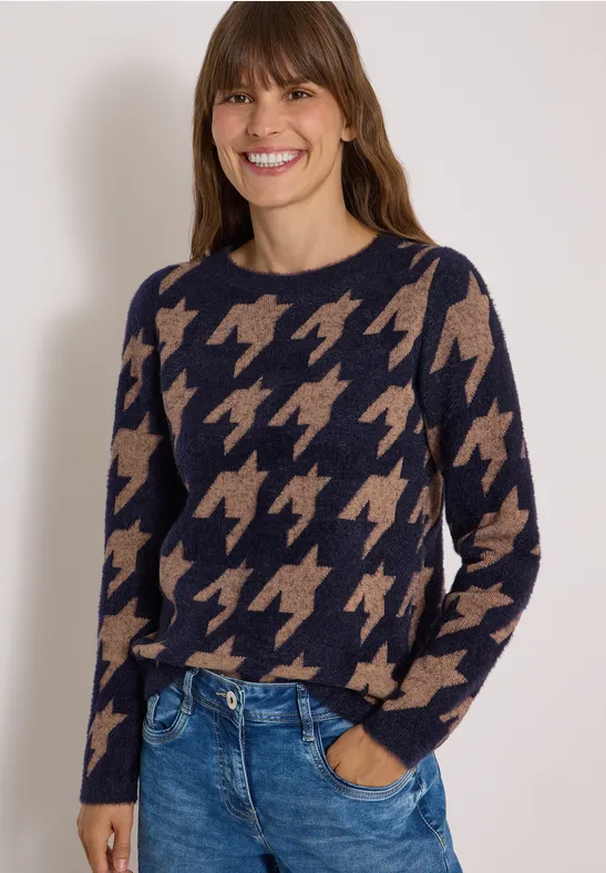 Femme souriante en pull bleu marine à motif pied-de-poule beige et jean