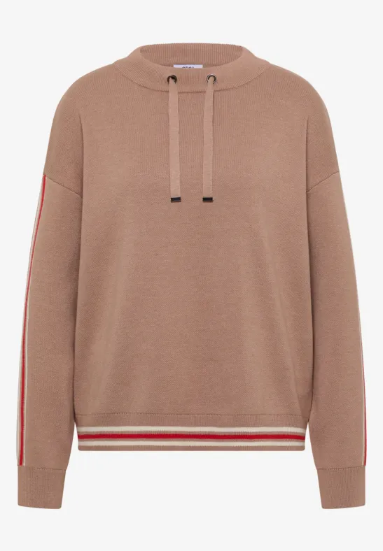 Beiger Hoodie mit Kapuze, roten Seitenstreifen an den Ärmeln und rot-weiß gestreiftem Saum.