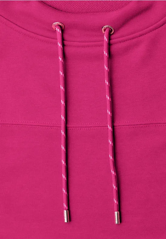 Close-up van een roze hoodie met tweekleurige aantrekkoorden en zilverkleurige uiteinden.