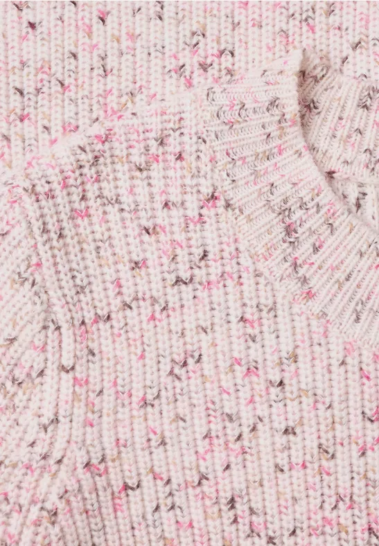 Nahaufnahme eines cremefarbenen, gerippten Strickpullovers mit zartrosa Sprenkeln.