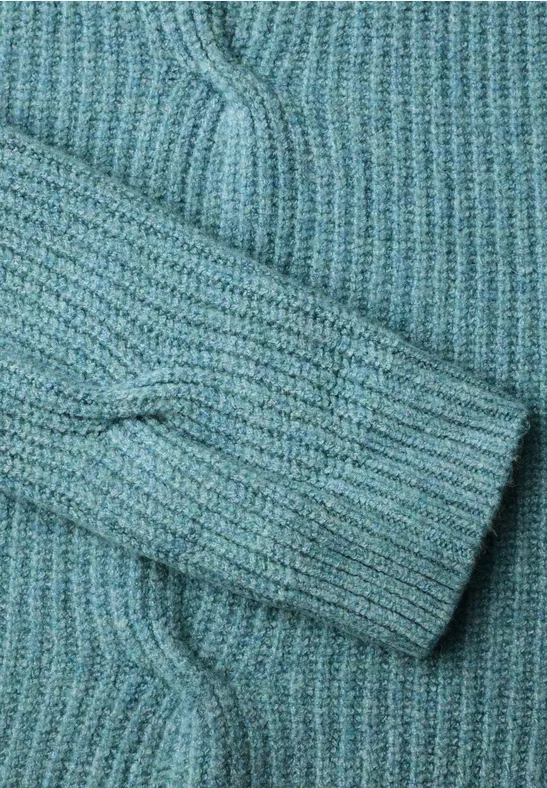 Nahaufnahme eines türkisfarbenen Strickpullovers mit Zopfmuster.