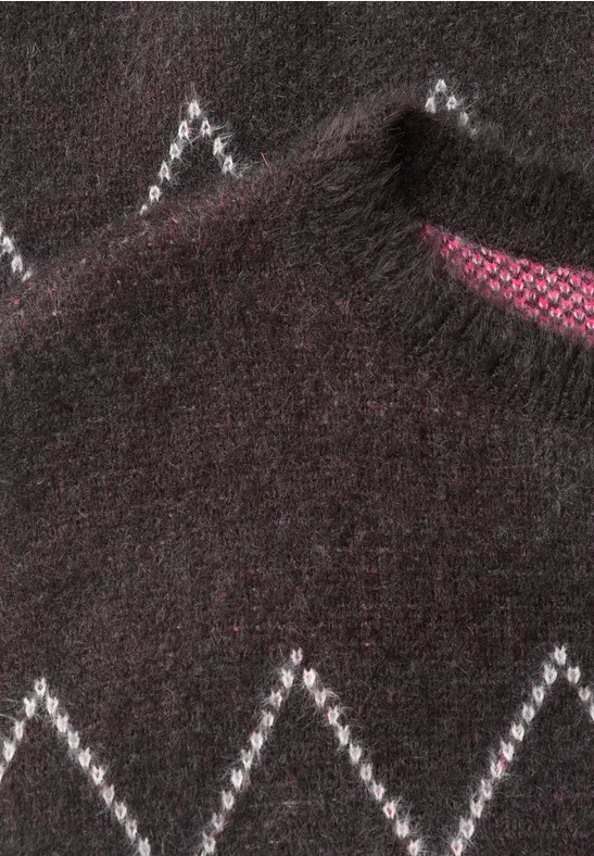 Ein dunkler Pullover mit weißem Zickzackmuster und pinkem Innenfutter am Kragen.