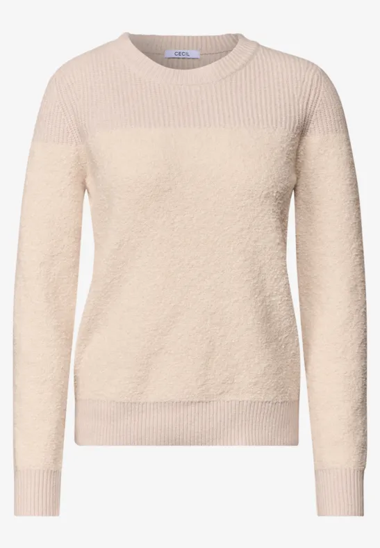 Beige damestrui van zacht, pluizig materiaal met ronde hals en lange mouwen.