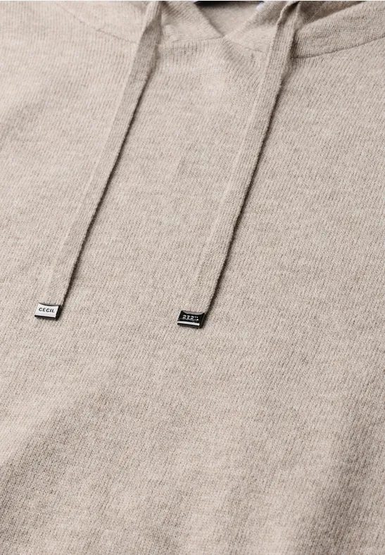 Beige Kapuzenpullover mit Kordelzug im Detail, weiche Struktur sichtbar.