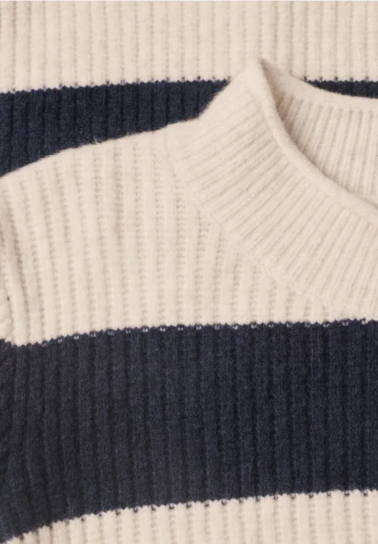 Gros plan sur un pull en maille à larges rayures crème et bleu marine.